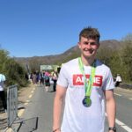 Smiling runner in an ALONE 'You're Not Alone' T-shirt wearing a finisher's medal after a marathon