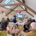 Speaker presenting to a seated audience at an ALONE volunteer information event in a beamed attic room