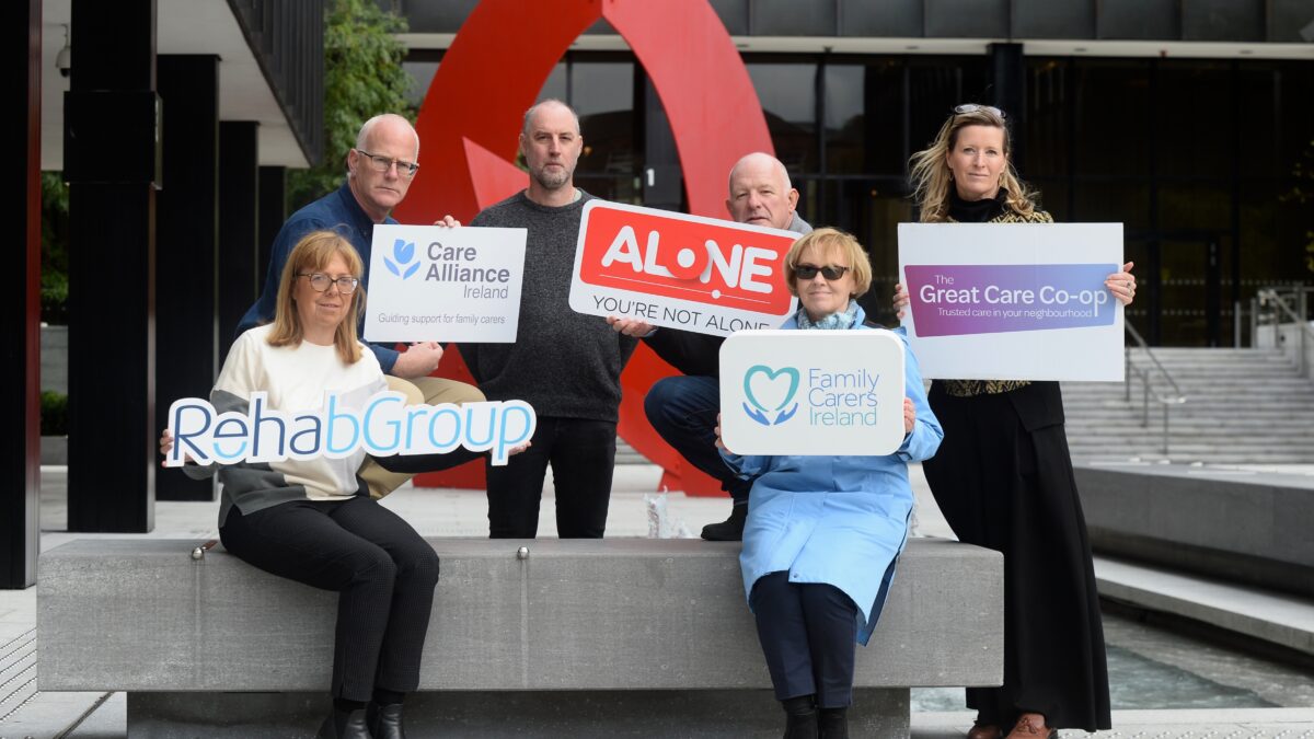 Six people hold signs for Rehab Group, Care Alliance Ireland, ALONE, Family Carers Ireland and The Great Care Co-op
