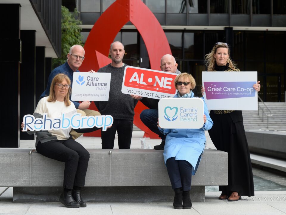 Six people hold signs for Rehab Group, Care Alliance Ireland, ALONE, Family Carers Ireland and The Great Care Co-op