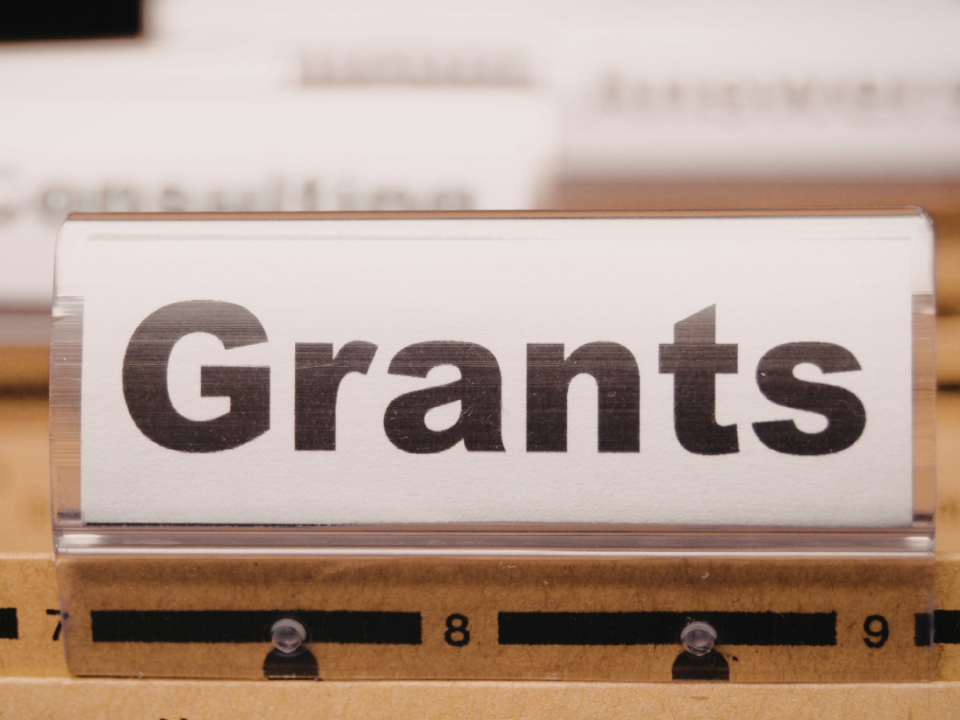 Filing cabinet tab labelled "Grants" among folders in a document drawer