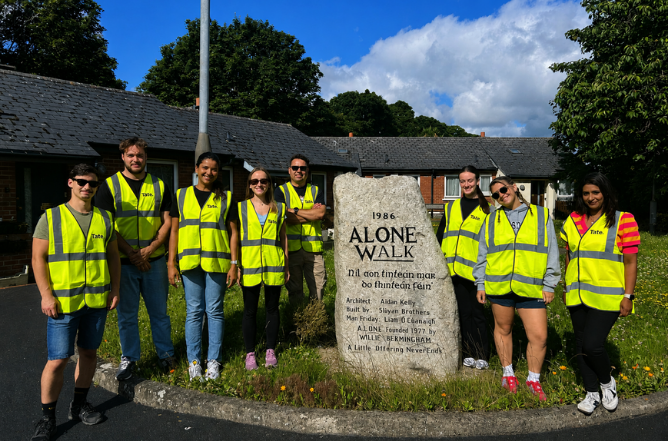 Group of corporate volunteers in high-visibility vests beside the 1986 ALONE Walk stone marker